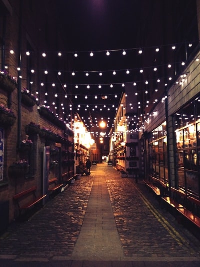 狭窄的街道与灯泡的照片在晚上的时间
